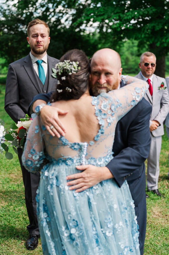 Bride's father gives her a hug as he gives her away to be married. 