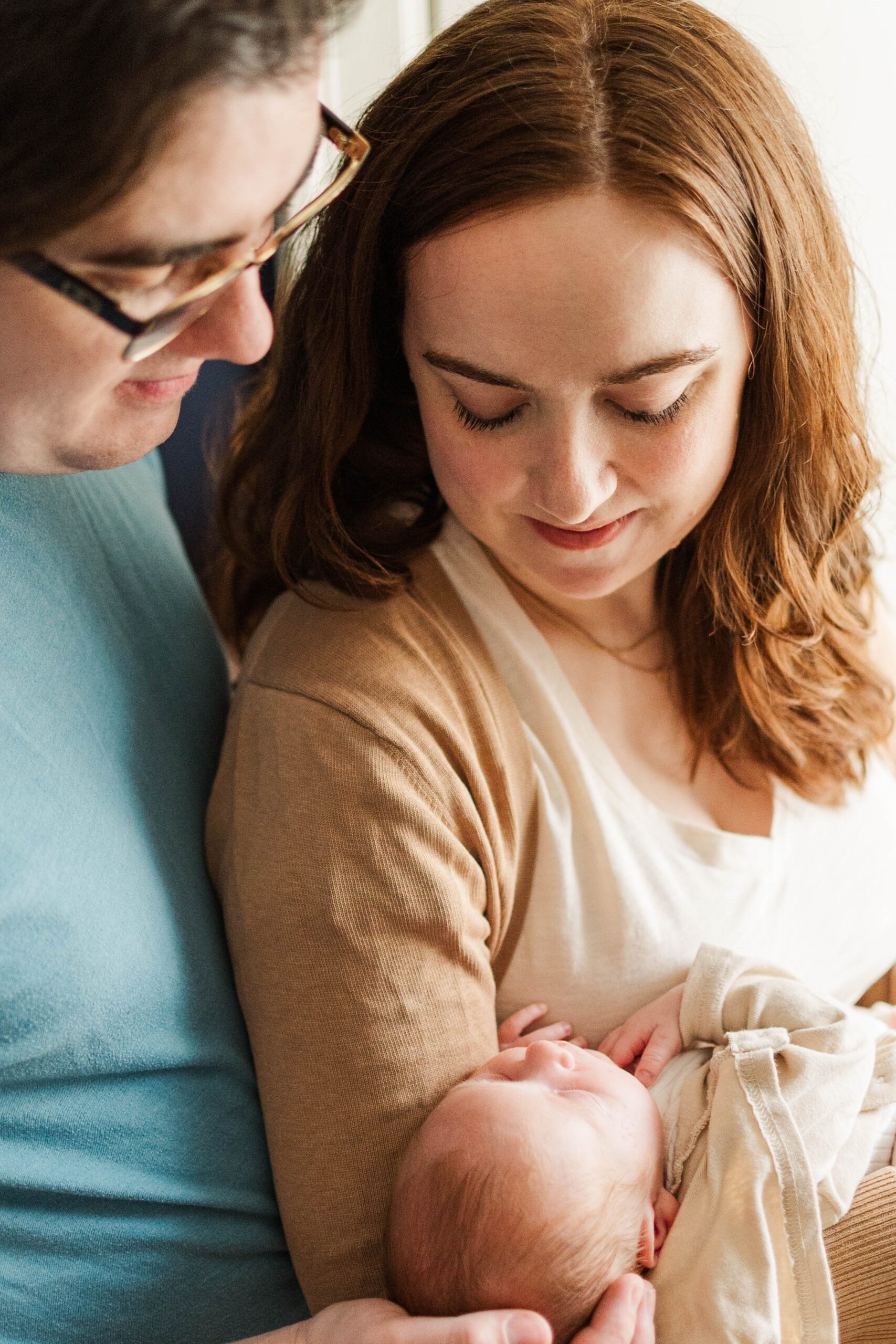 New mom and dad hold their newborn baby in the nursery of their house