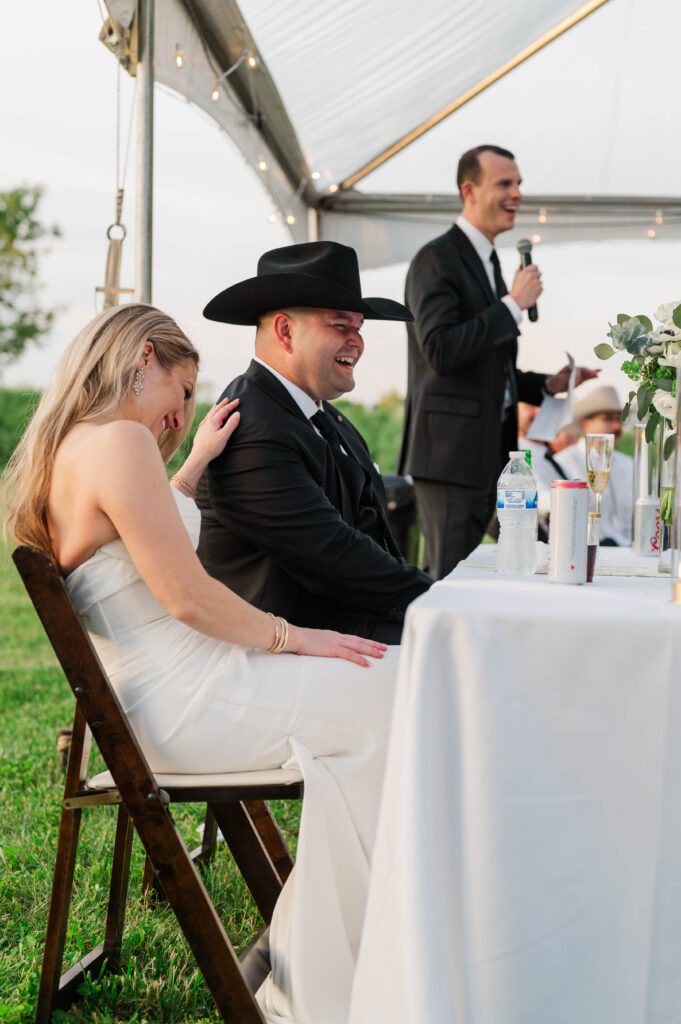 Bride and groom react to toasts given at their wedding reception