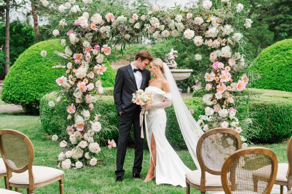 Bride and groom stand in front of their ceremony arch on their wedding day 