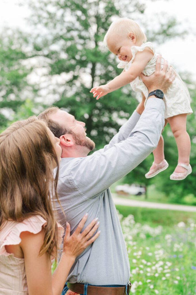 Mom and dad hold their baby girl in the air for their Louisville family session.