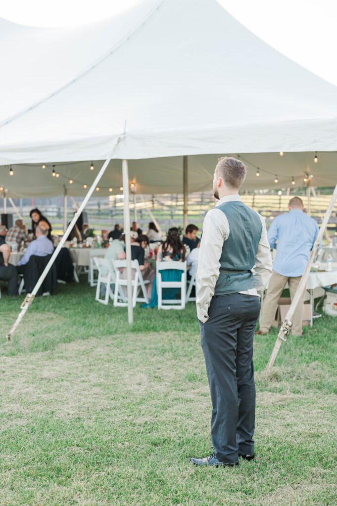 Groom stands taking in his wedding reception during his Taylorsville, Kentucky wedding. 