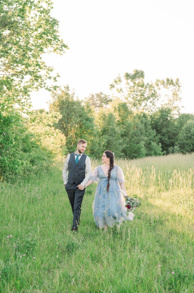 Bride and groom walk through a field on their Kentucky farm wedding day.