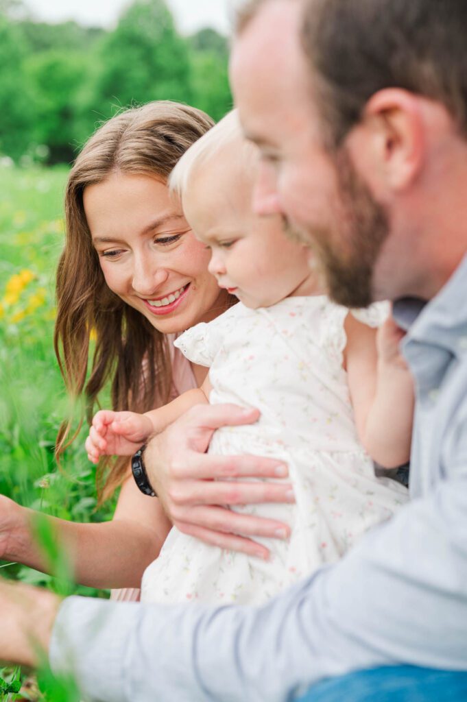 Mom, dad, and baby look at the wildflowers