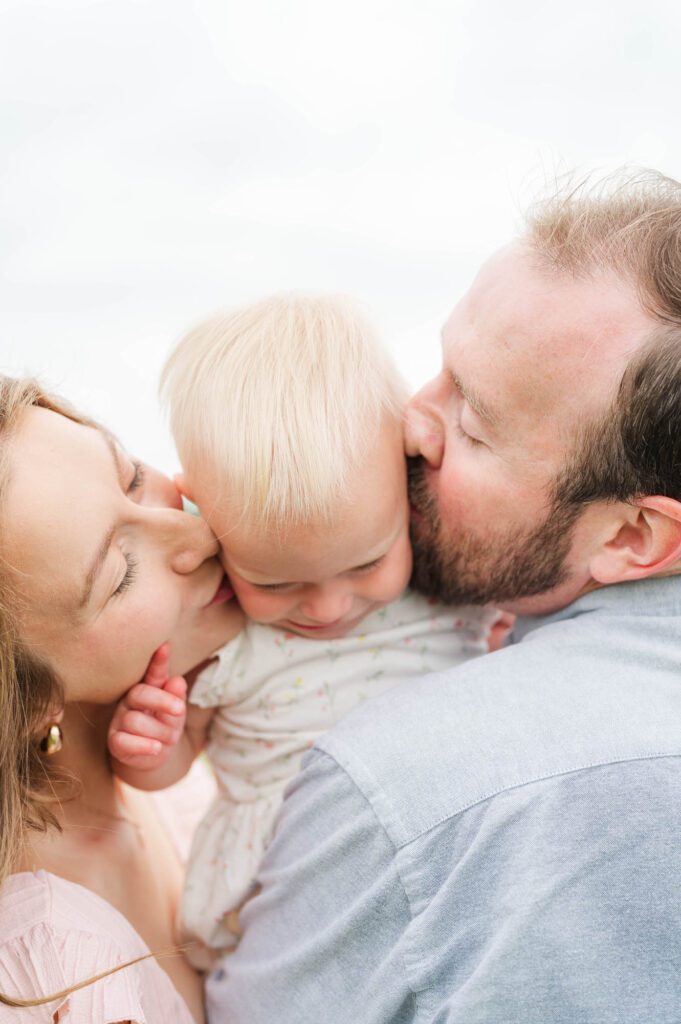 Mom and dad kiss their daughter