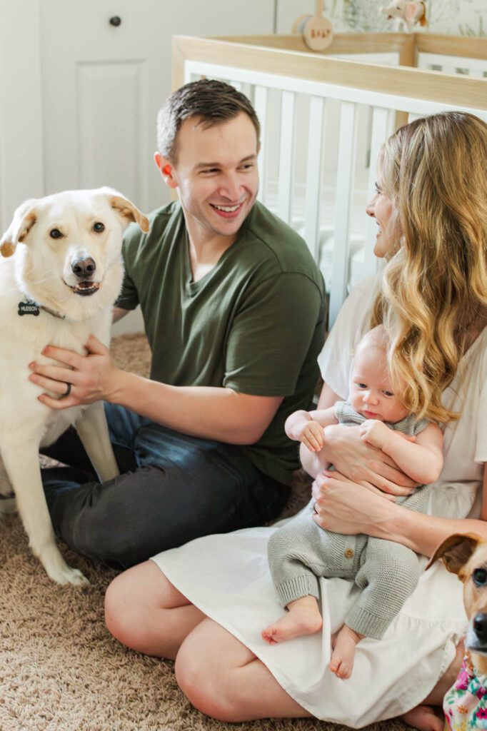 Family sits together in the nursery with their 3 month old and their dogs for their Louisville in-home family session