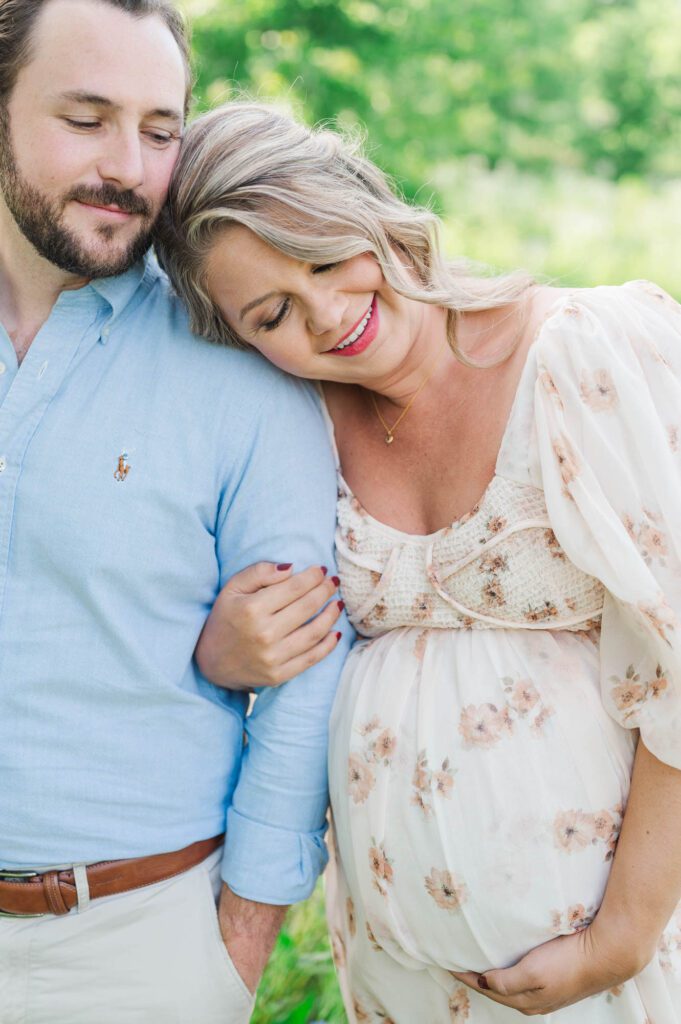 Couple stands together in wildflower field for their maternity photo session at Beckley Creek Park in Louisville