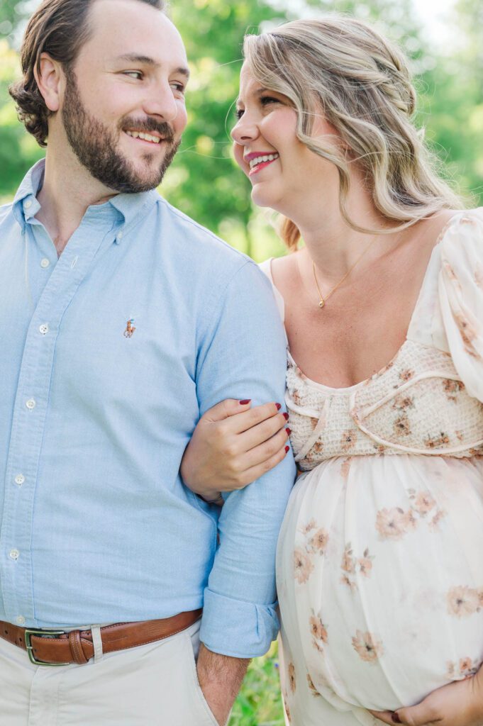 Couple stands together in wildflower field for their maternity photo session at Beckley Creek Park in Louisville