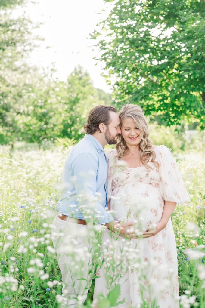 Couple stands together in wildflower field for their maternity photo session at Beckley Creek Park in Louisville