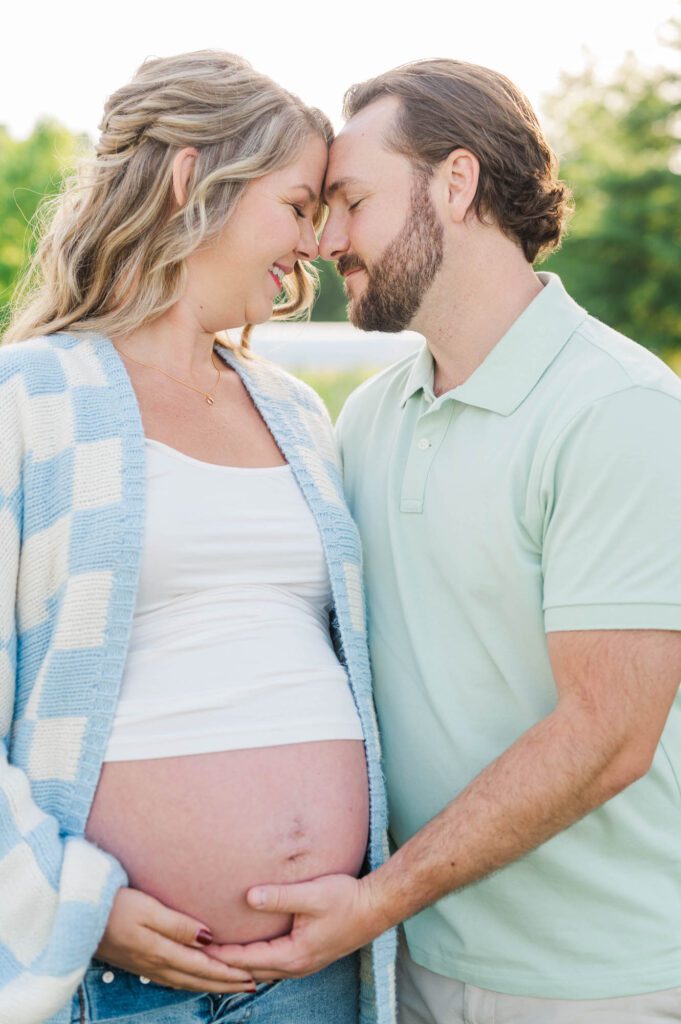 Couple stands together in wildflower field for their maternity photo session at Beckley Creek Park in Louisville