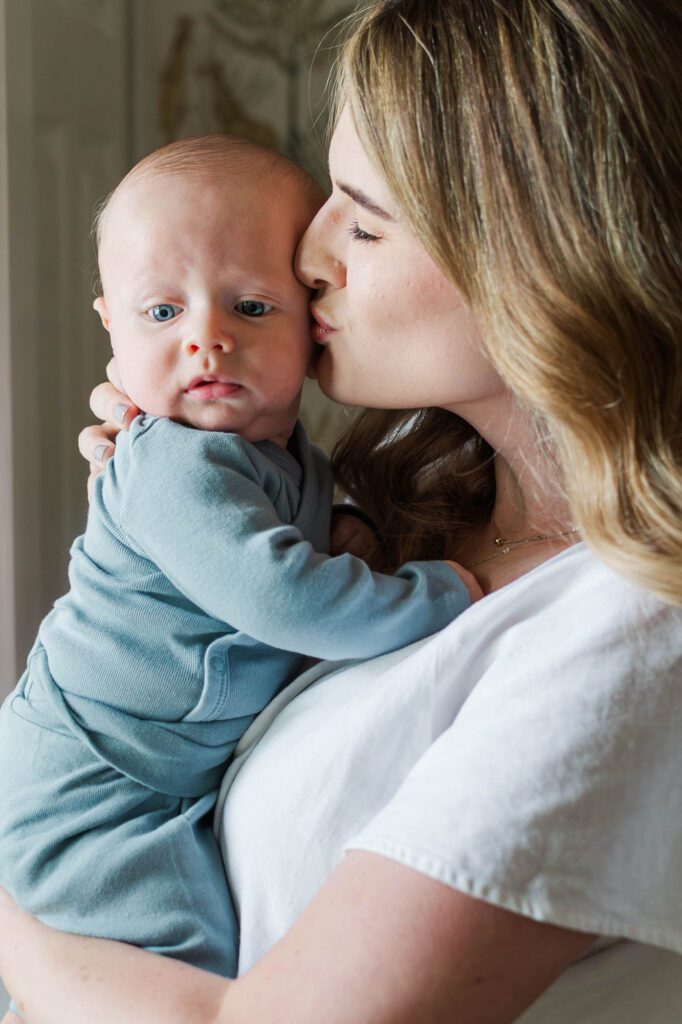 Mom kisses her son during his three month milestone session