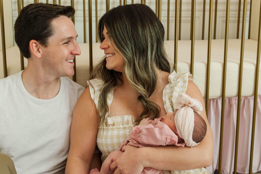 New mom and dad hold their baby girl in the nursery for their Louisville, KY in-home newborn session