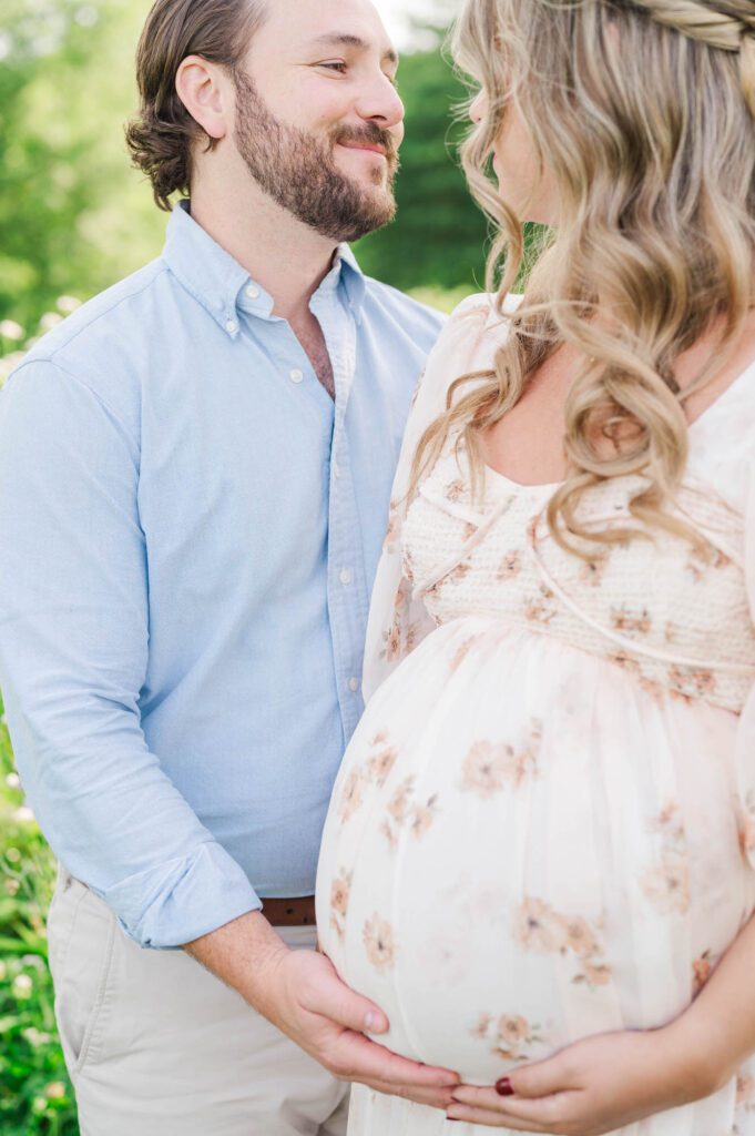 Couple stands together in wildflower field for their maternity photo session at Beckley Creek Park in Louisville