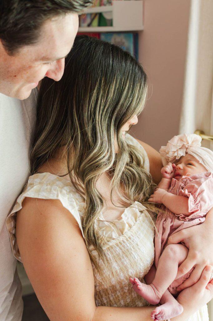 New mom and dad hold their baby girl in the nursery for their Louisville, KY in-home newborn session