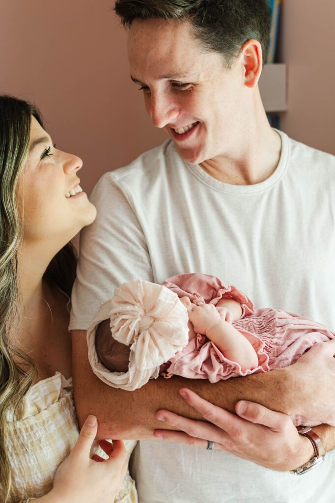 New mom and dad hold their baby girl in the nursery for their Louisville, KY in-home newborn session