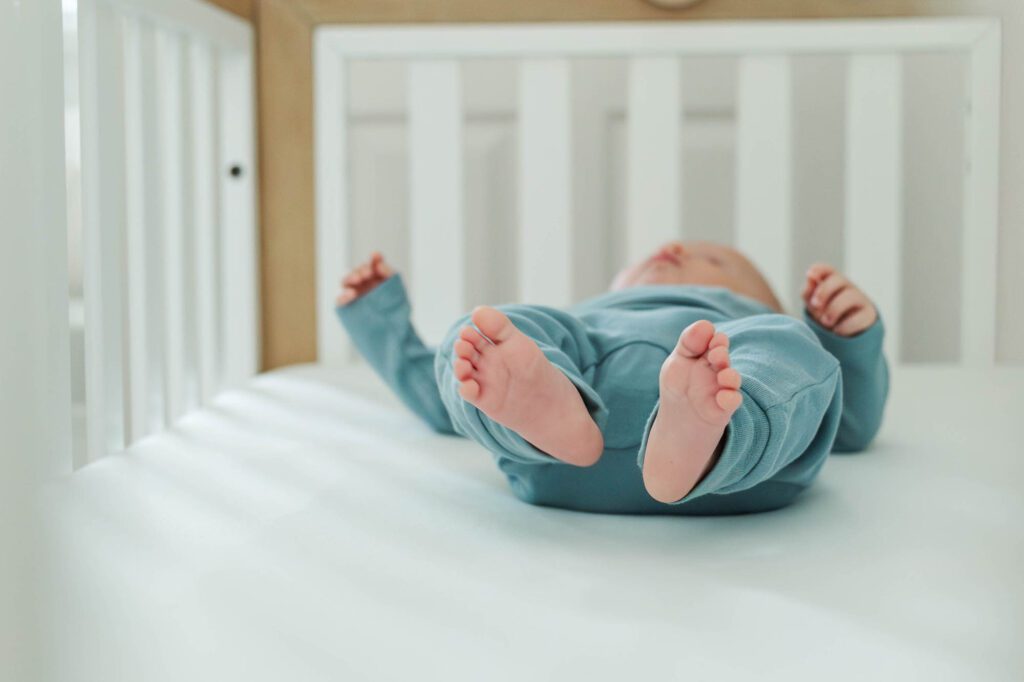 Baby lays in his crib for his 3 month milestone session