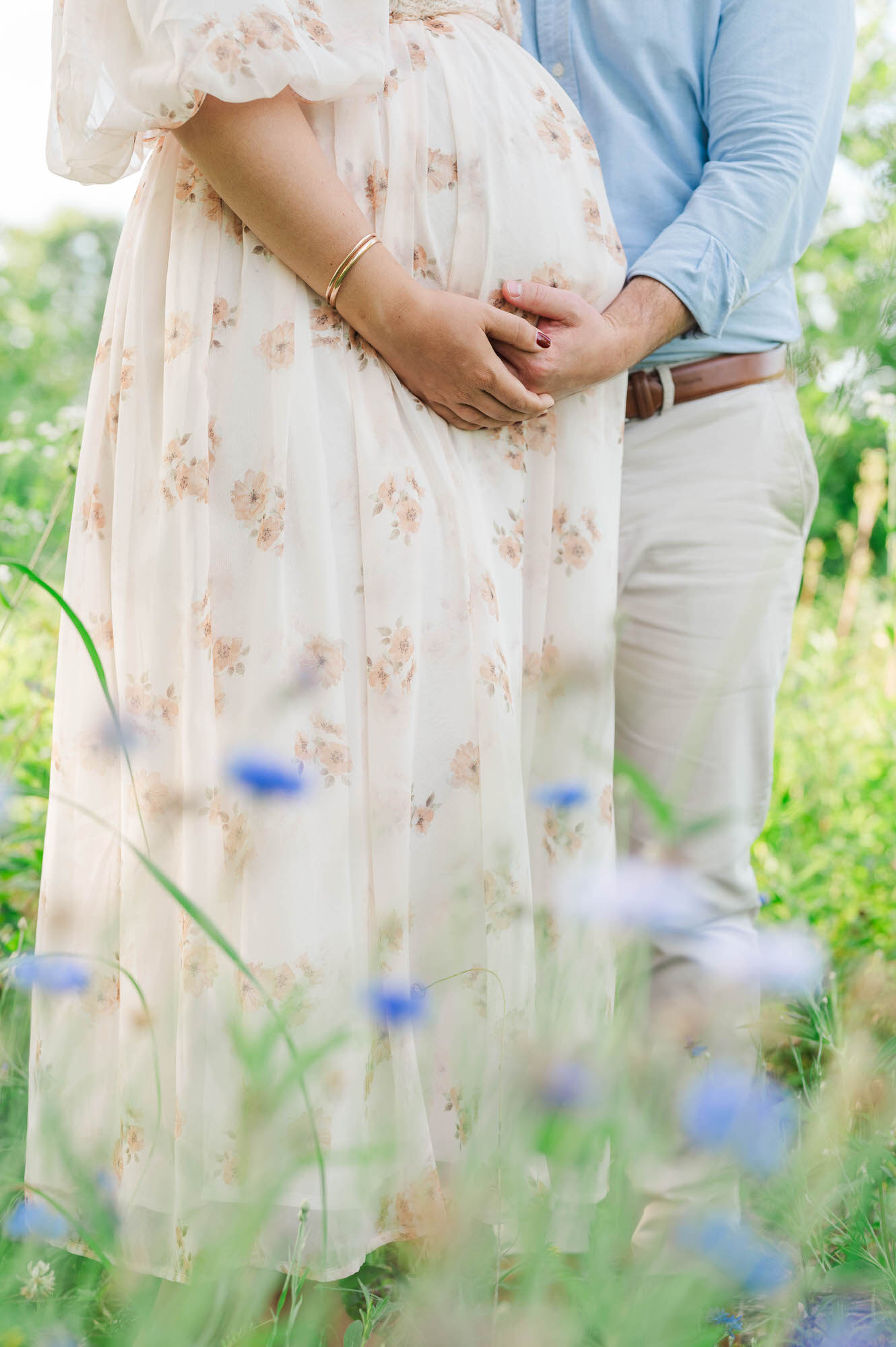 A couple stands together behind the wildflowers for their maternity session in Louisville, KY