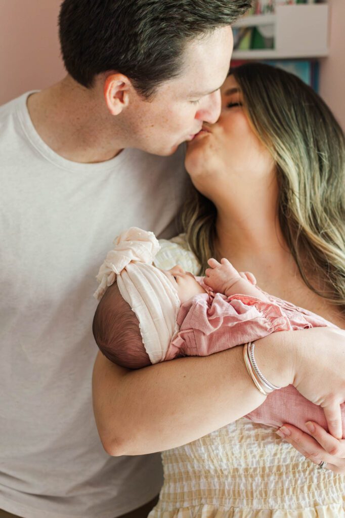 New mom and dad hold their baby girl in the nursery for their Louisville, KY in-home newborn session