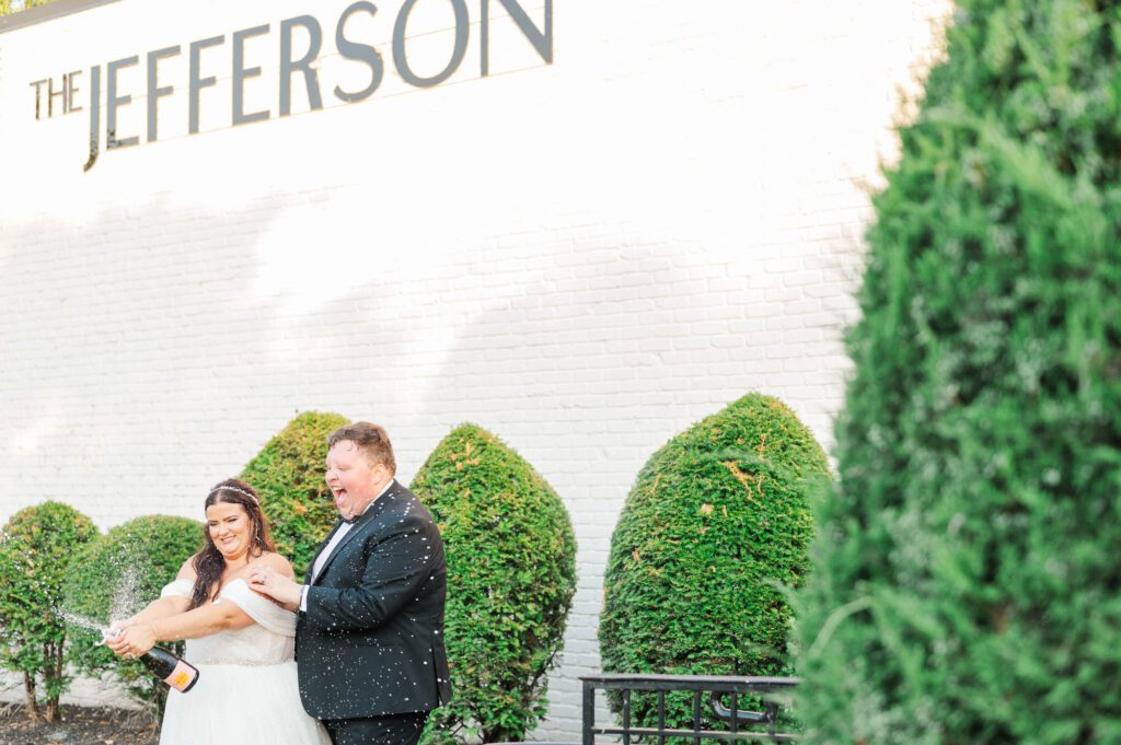 Bride and groom pop a bottle of champagne on their wedding day at the Jefferson