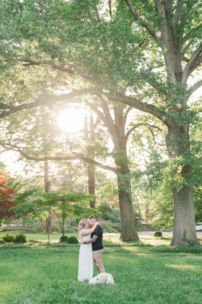 Far away shot of a couple and their dog under a tree at the Anchorage Trail in Louisville, KY