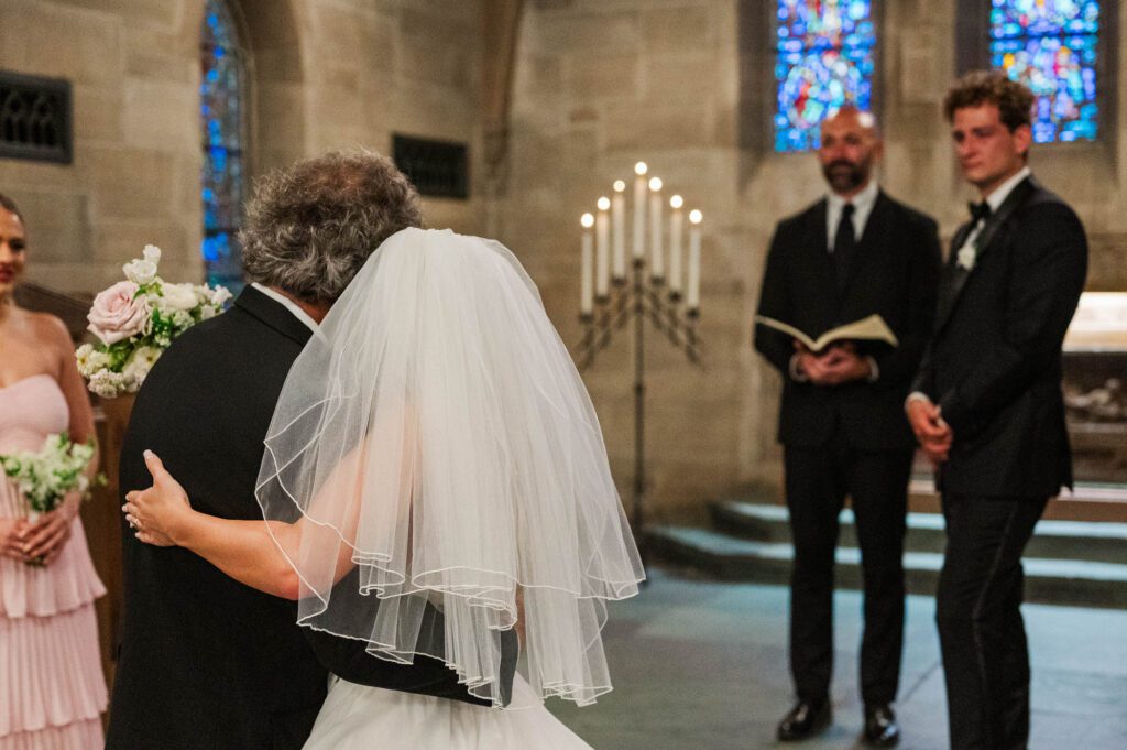 Bride gives her dad a hug as he gives her away at the ceremony