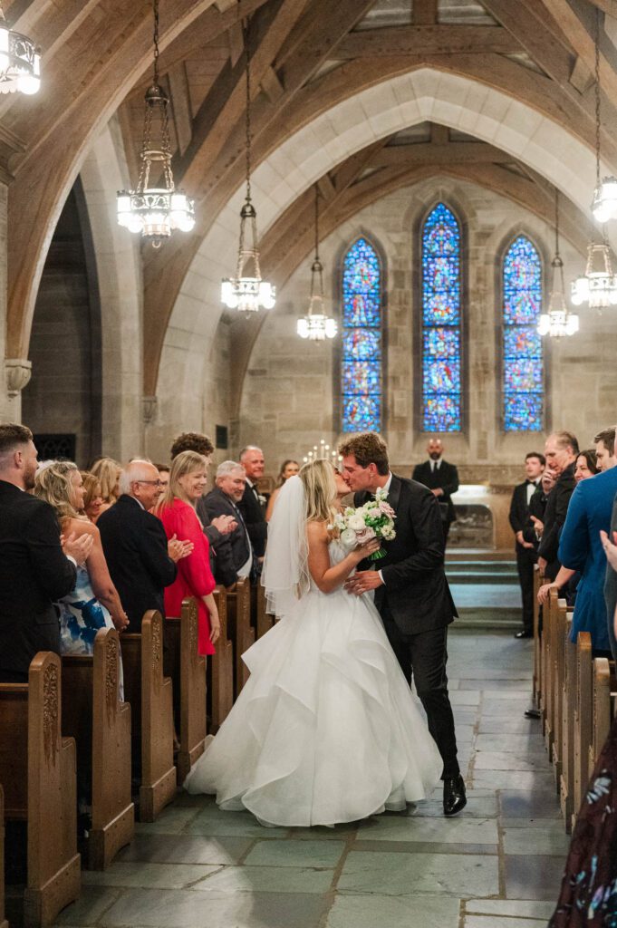 Bride and groom kiss as they walk back down the aisle after being married