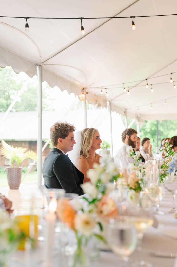 Bride and groom listen to speeches during their wedding reception