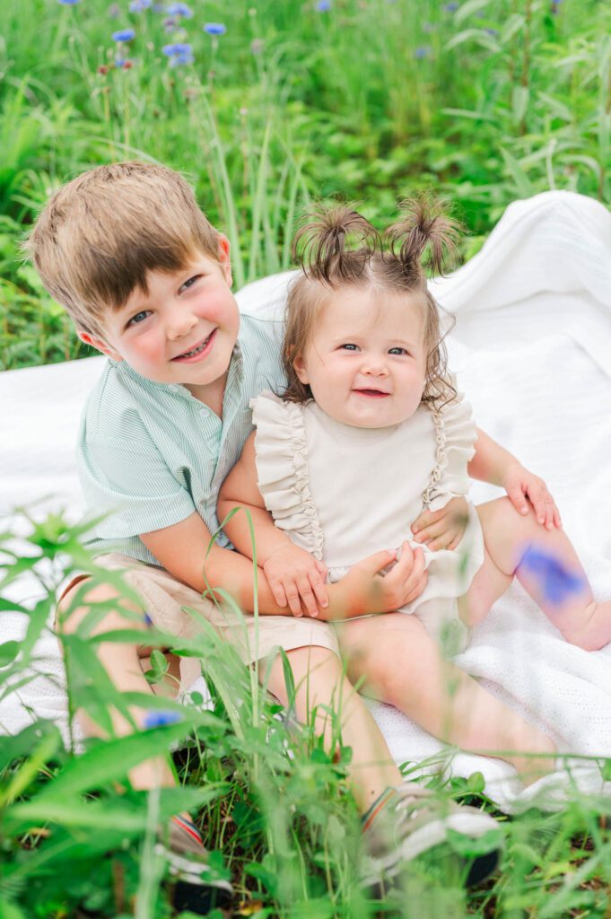 Brother and sister sit together on a blanket at Beckley Creek Park