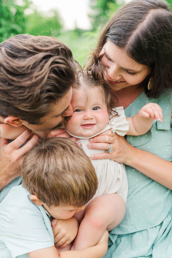 Family hugs and kisses baby sister for their photo session in Louisville, KY