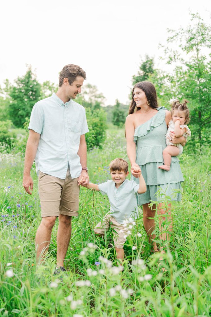 Family walks through field of wildflowers for their photo session in Louisville, KY