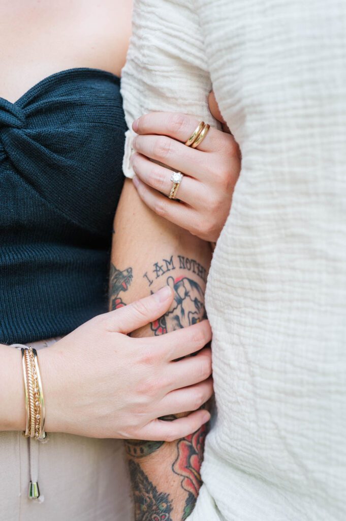 A close up of a couple holding hands and their wedding rings during a photo session