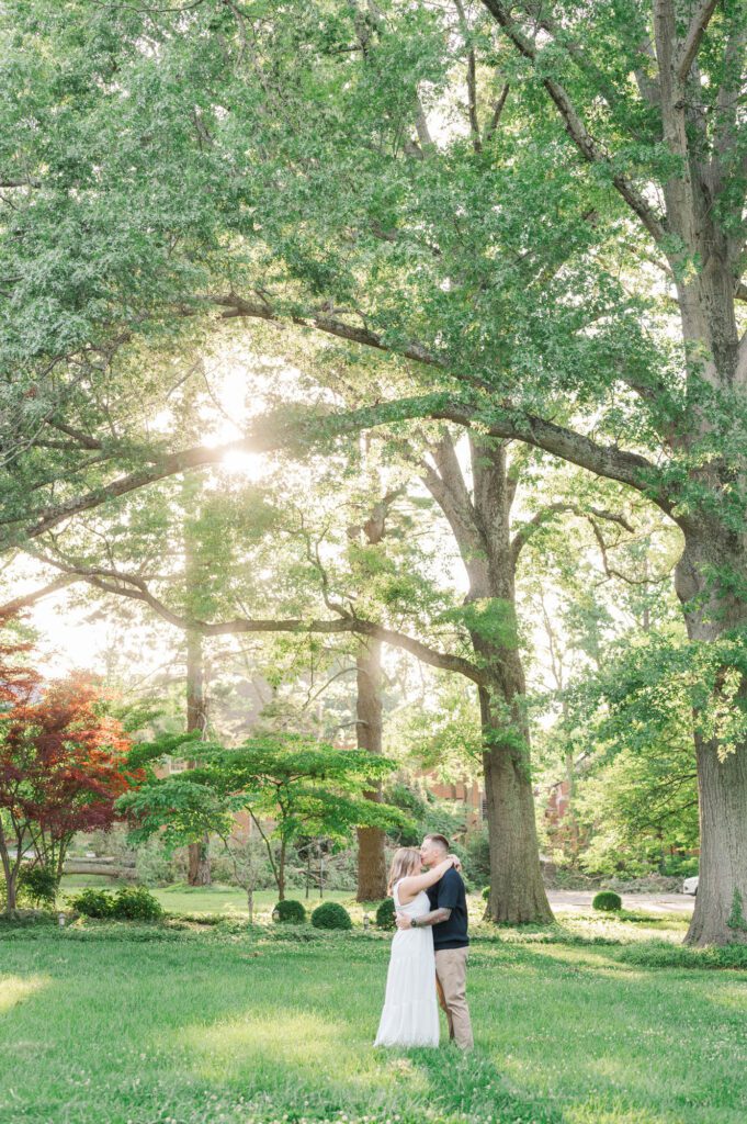 Far away shot of couple giving a kiss under a tree at Anchorage Trail