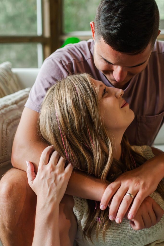 Couple looks lovingly at one another sitting together on their back porch