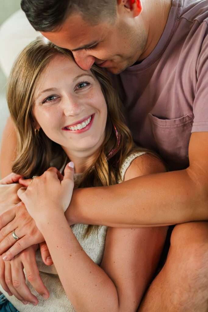 Couple sits together on their couch for their in-home couples session in Louisville, KY