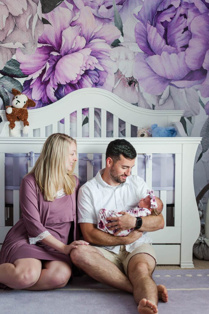 New parents smile while holding their baby girl during their in-home newborn photography session in Lexington, KY