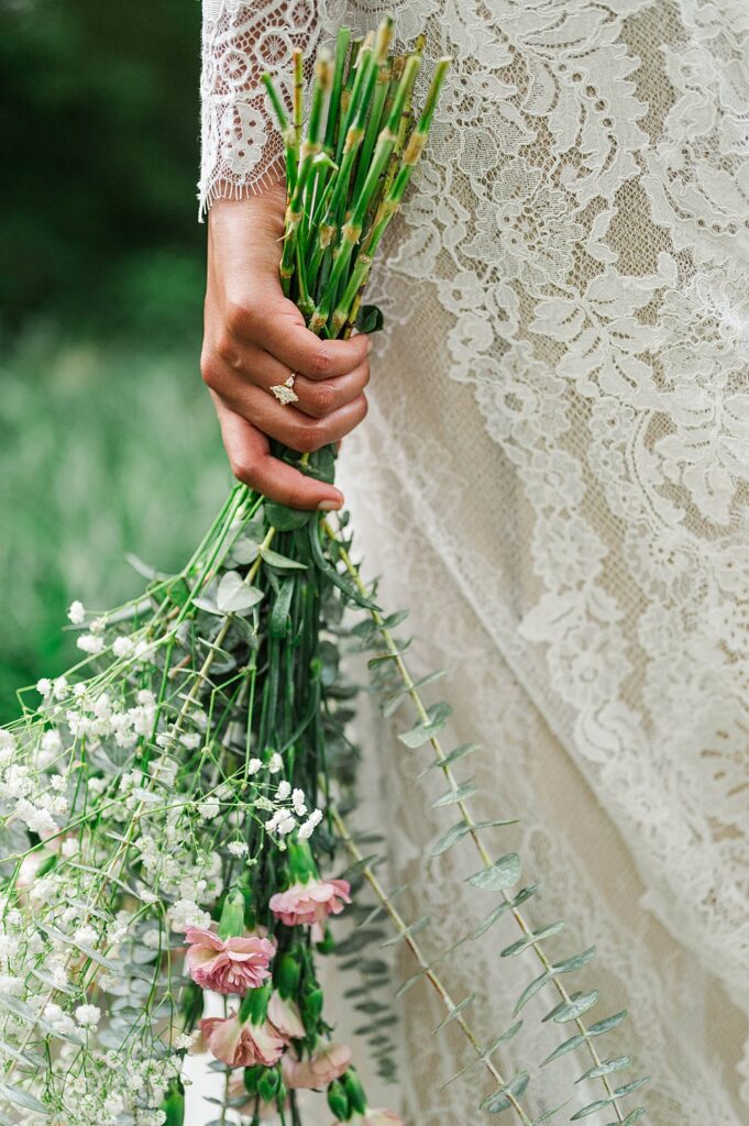 Close up of a bridal bouquet with a lace wedding dress in the background