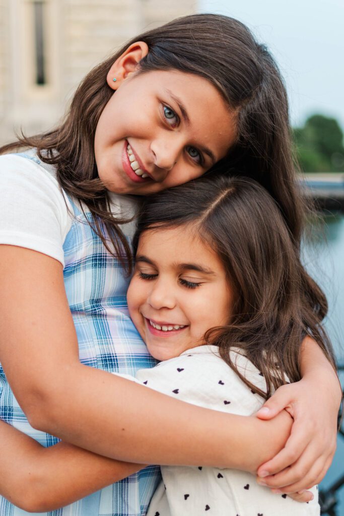 Sisters hug during their family session