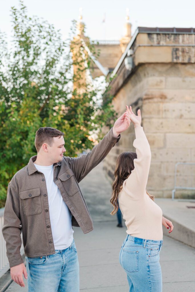 Couple twirls at Roebling Bridge for their Cincinnati engagement photos