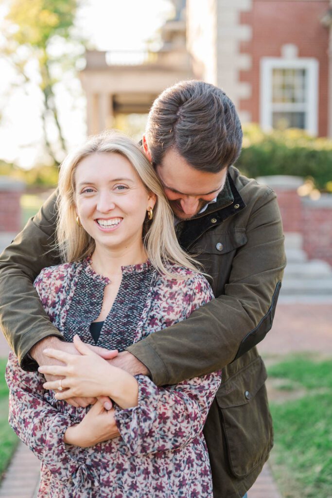 Couple smiles in front of the camera at Gardencourt in Louisville for their engagement session