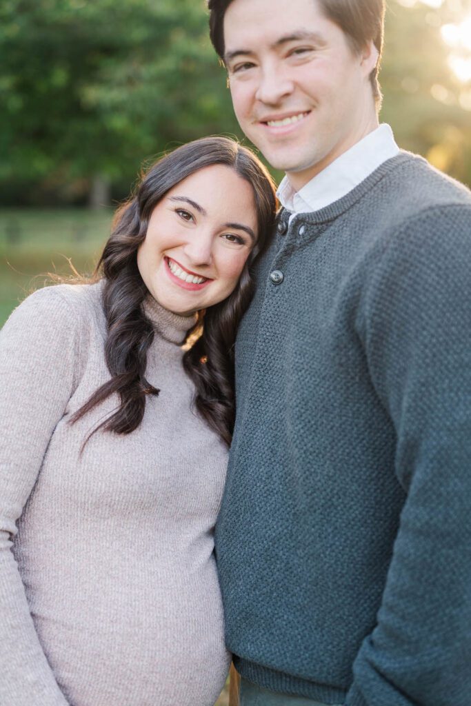 Parents-to-be smile at the camera during their maternity session at Cherokee Park