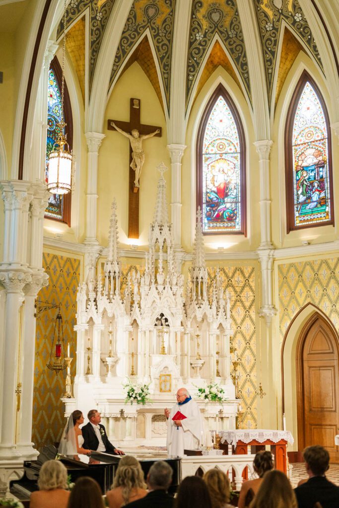 Bride and groom listen to sermon at their Catholic Mass ceremony at Summit Country Day