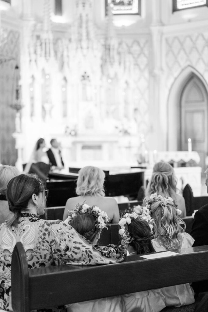 Flower girls sitting in the pew with bride and groom in background for their wedding at Summit Country Day in Cincinnati