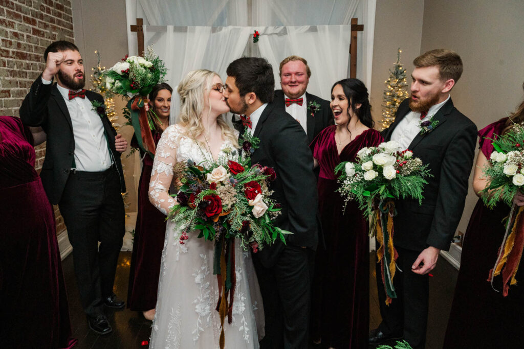 Bride and groom share a kiss in front of their bridal party