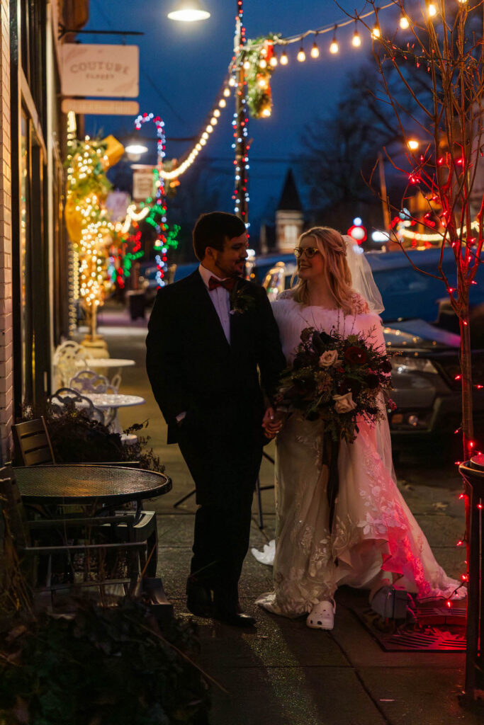 Bride and groom walk down Main St La Grange, KY with Christmas lights in the background