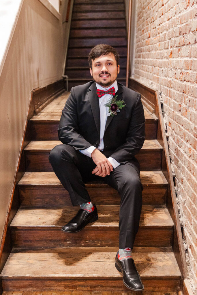 Groom sits on the stairs at The Gatewood