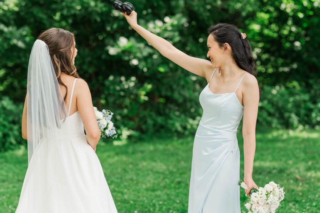 Bridesmaid uses a fan to cool off the bride at her Gheens Foundation Lodge wedding