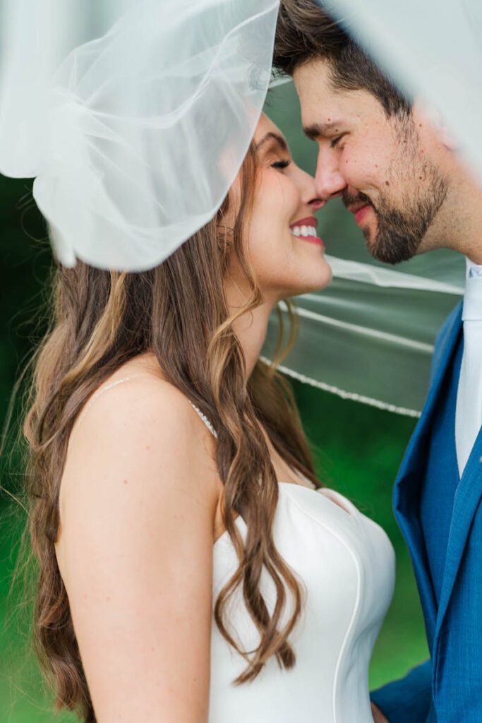 Newlyweds nuzzle together under the veil for a portrait at their Gheens Foundation Lodge wedding in Louisville, KY