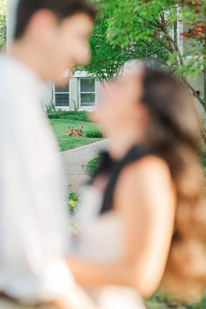 Couple smile at each other with deer in the background during their engagement session at Anchorage Trail in Louisville, KY