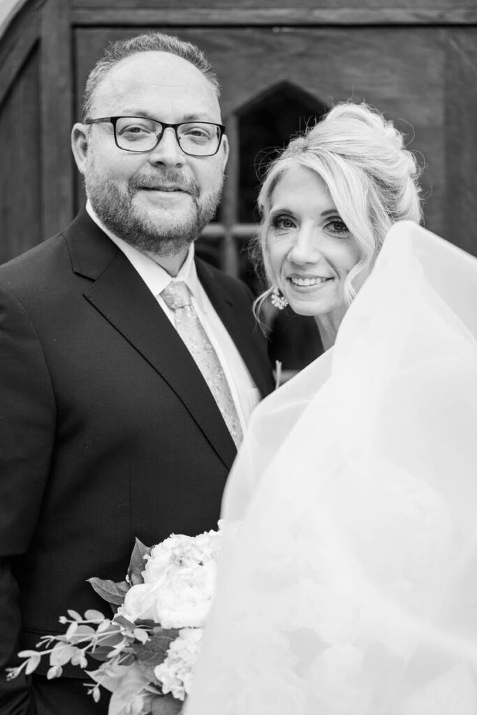 Bride and groom stand in front of their wedding ceremony site, Duncan Memorial Chapel