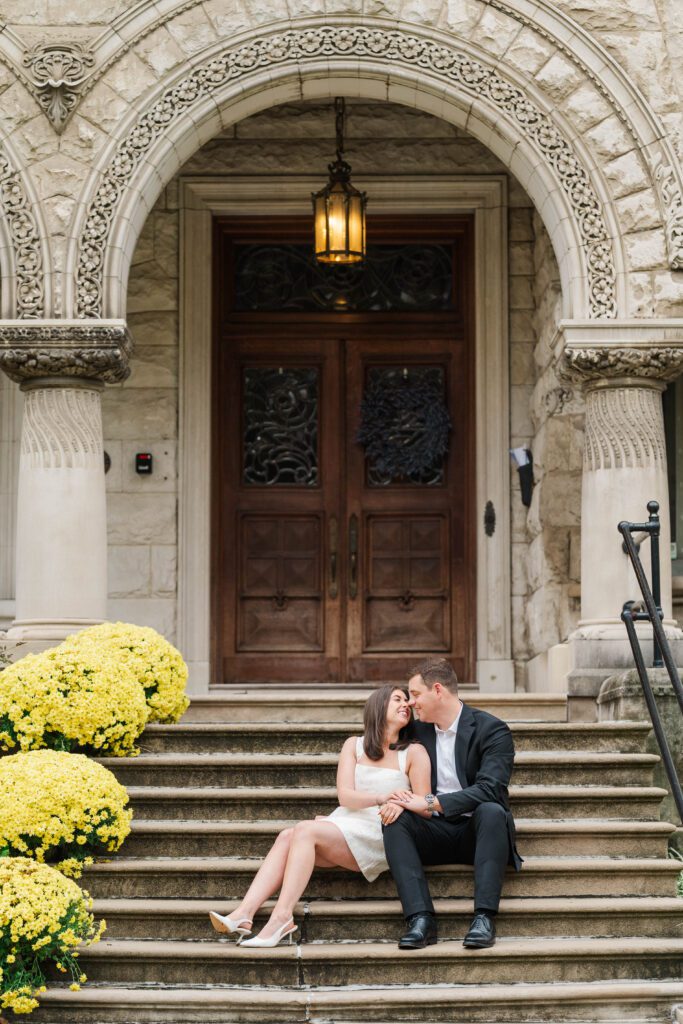 Engaged couple sits together on stairs at Saint James Court in Louisville, Ky